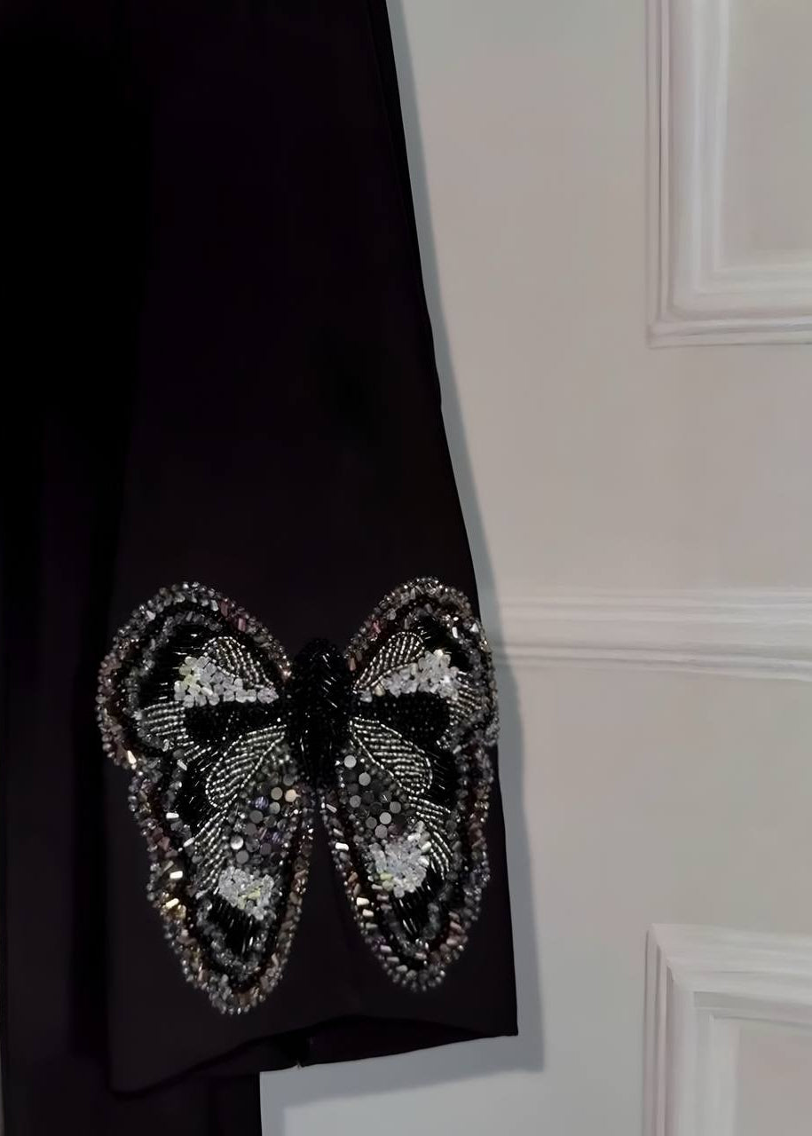 Black fabric with a butterfly-shaped embellishment on a neutral background