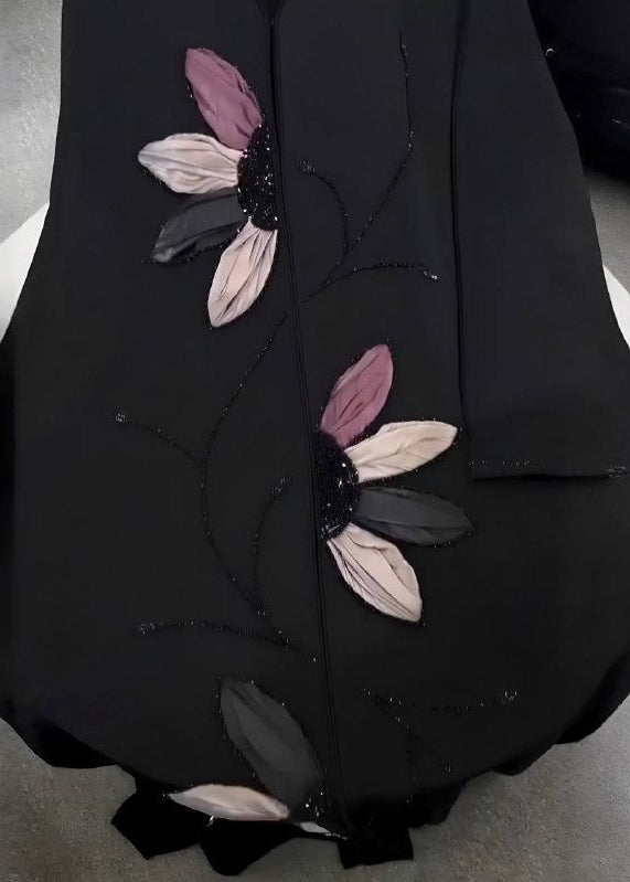 Black garment with floral embroidery on a gray background